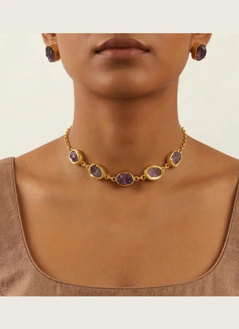 Gold necklace featuring raw amethyst stones, paired with matching studs