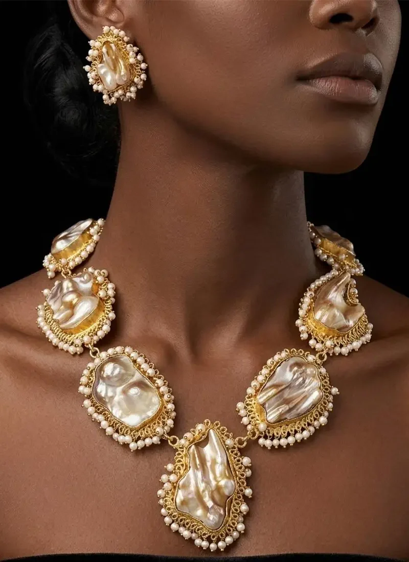 Pearl-embedded intricate statement gold necklace with matching earrings and finger ring.