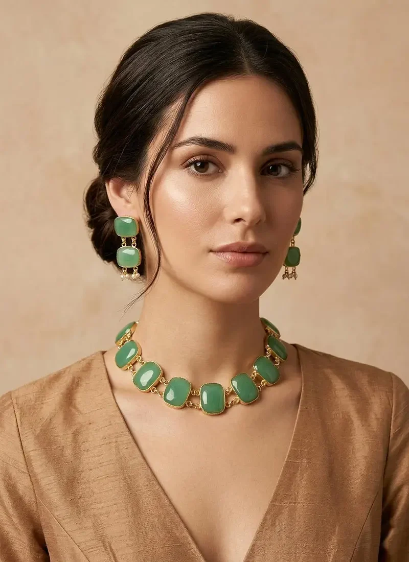 Gold necklace set featuring emerald green Monalisa stones, paired with matching drop earrings.