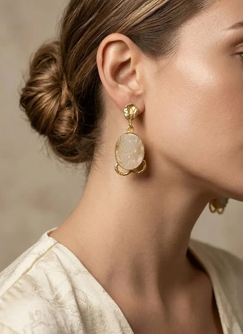 White druzy stone hanging earrings on a gold base.