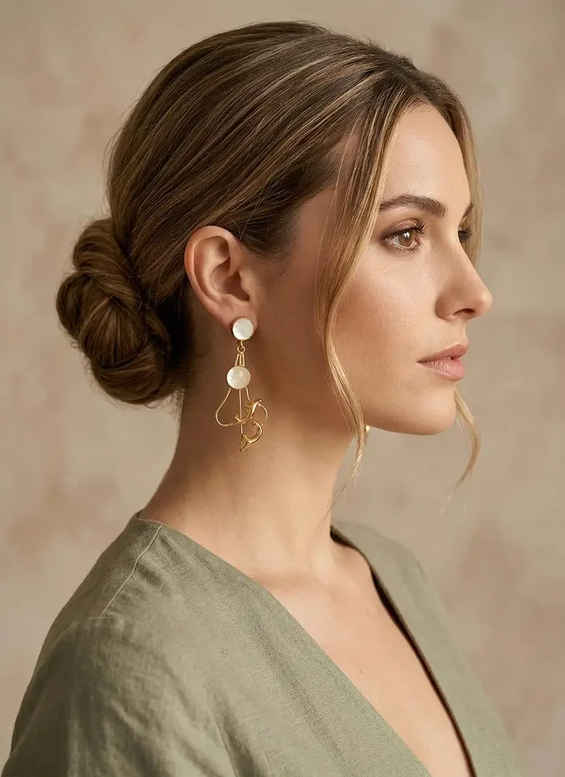 Mother of pearl earrings with a sculpted golden accents.